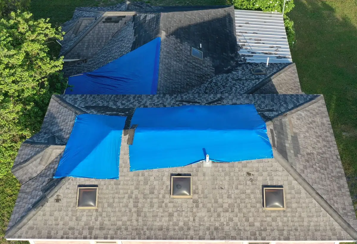 Damaged shingle roof covered with tarps before replacement in Mission, Texas